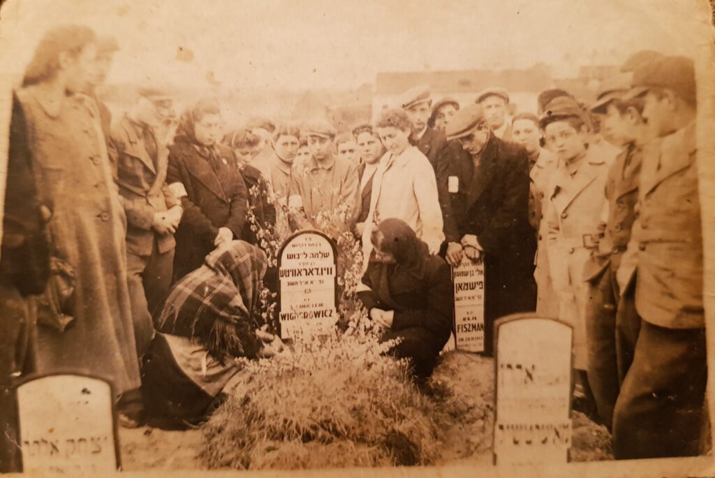 4 tombstones of the 36 murdered on Apr 28, 1942- Photo courtesy of Pinchas Wigdorowicz,/Vider z"l (His family is gathered at center of photo next to matzeva of his murdered brother Shlomo)